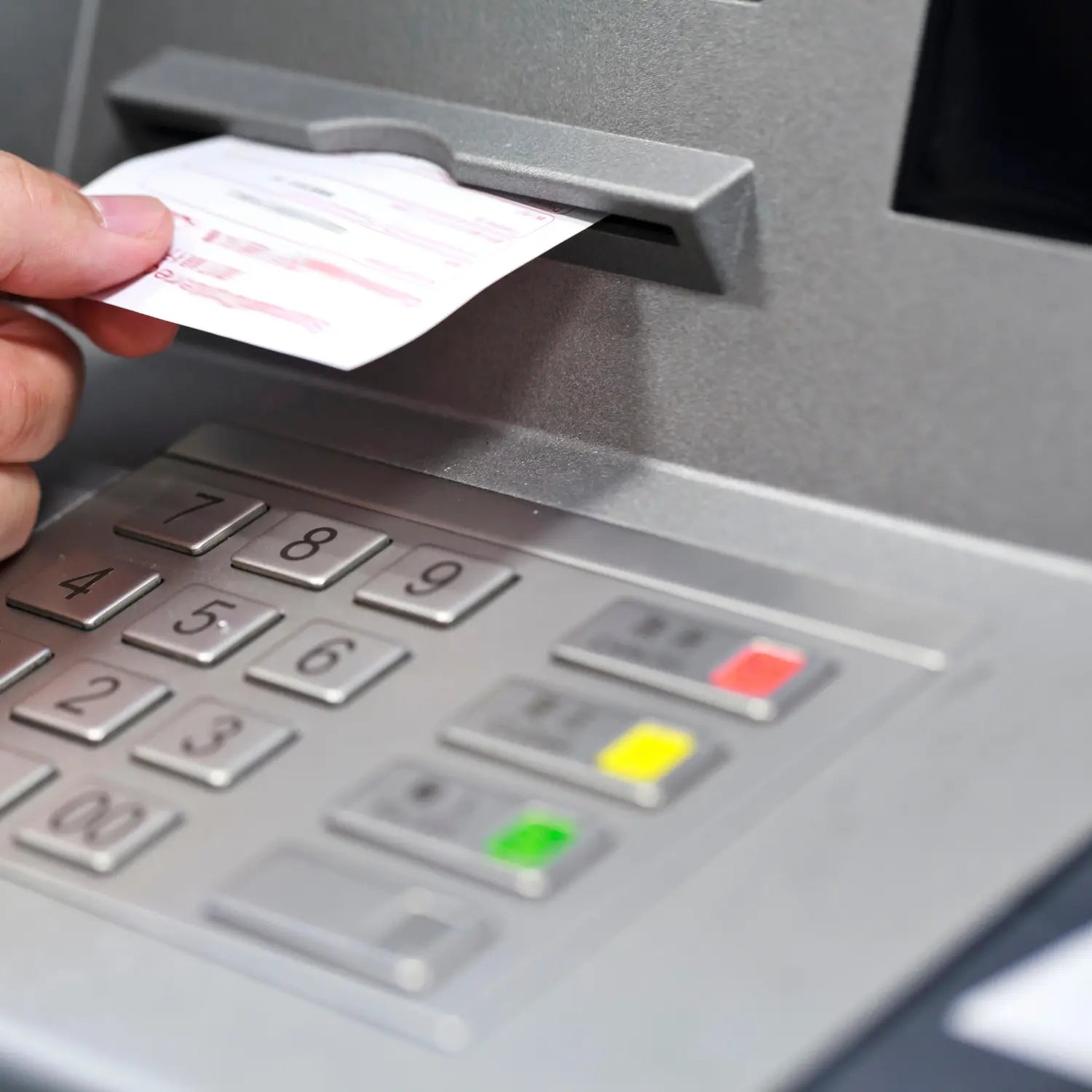 Main retirant un ticket d'un distributeur automatique de banque - Impression nette et durable sur bobines thermiques conformes aux exigences réglementaires - La Bobine Française.